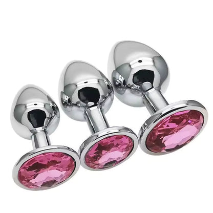 Three metallic butt plugs with pink gemstones on a white background